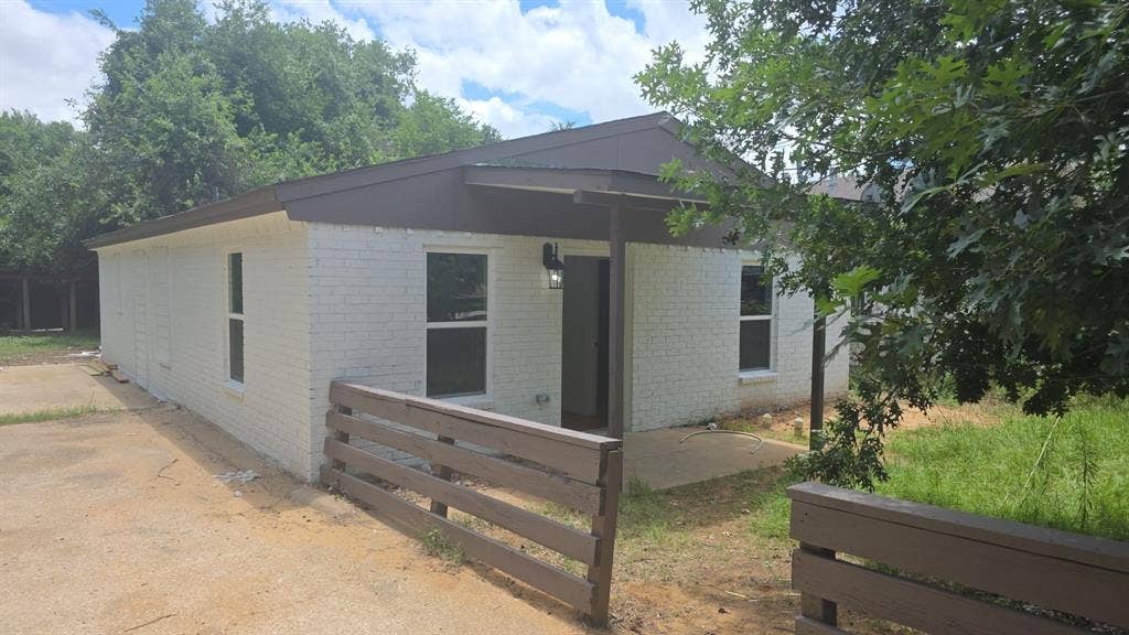 4643 Luzon Street, Dallas, TX 75216 Single-story residence featuring white painted brick exterior, dark-toned trim, front porch, and horizontal wood fencing