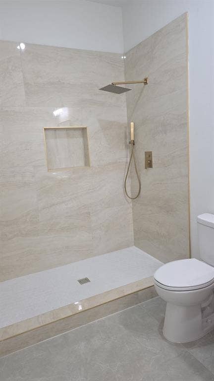 4643 Luzon Street, Dallas, TX 75216 Walk-in shower featuring large-format stone-finish tile surround, a built-in recessed niche, gold-toned rainfall showerhead with handheld sprayer, and a low-profile basin