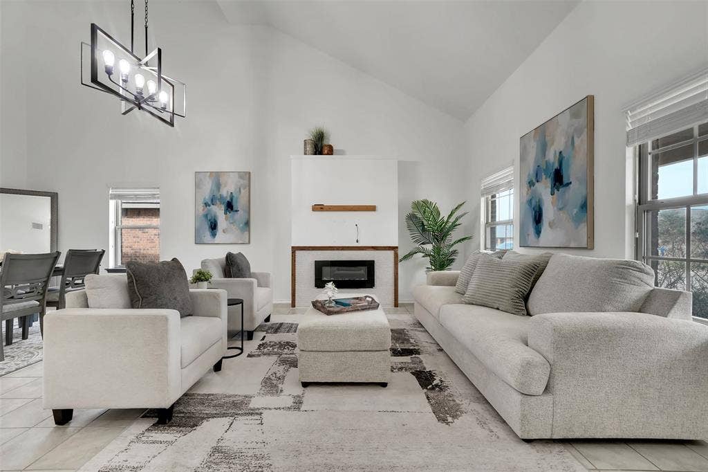 1121 Basswood Lane, Royse City, TX 75189 Tiled living room with a notable chandelier, a glass covered fireplace, and high vaulted ceiling