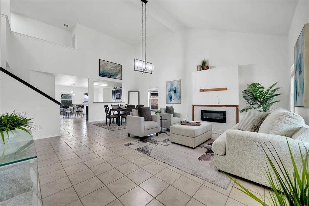1121 Basswood Lane, Royse City, TX 75189 Living area with baseboards, high vaulted ceiling, an inviting chandelier, light tile patterned flooring, and a glass covered fireplace