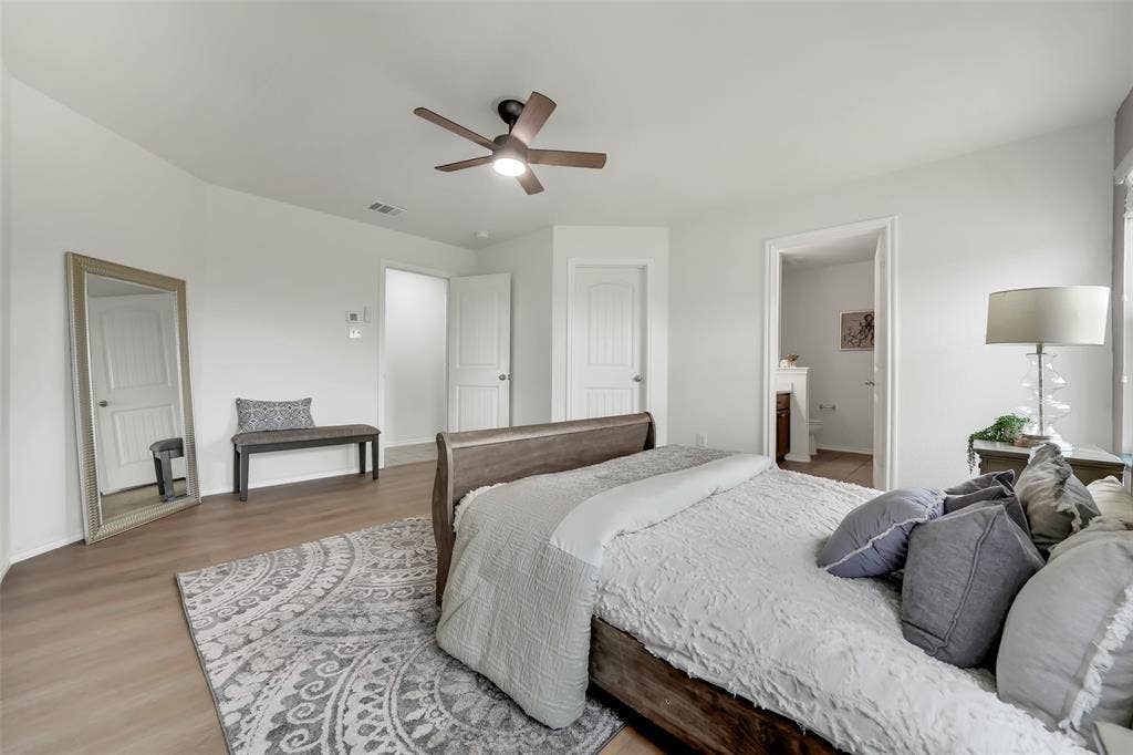 1121 Basswood Lane, Royse City, TX 75189 Bedroom with baseboards, visible vents, ensuite bath, ceiling fan, and light wood-type flooring