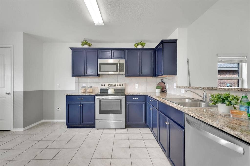 1121 Basswood Lane, Royse City, TX 75189 Kitchen featuring a sink, blue cabinetry, appliances with stainless steel finishes, light tile patterned flooring, and decorative backsplash
