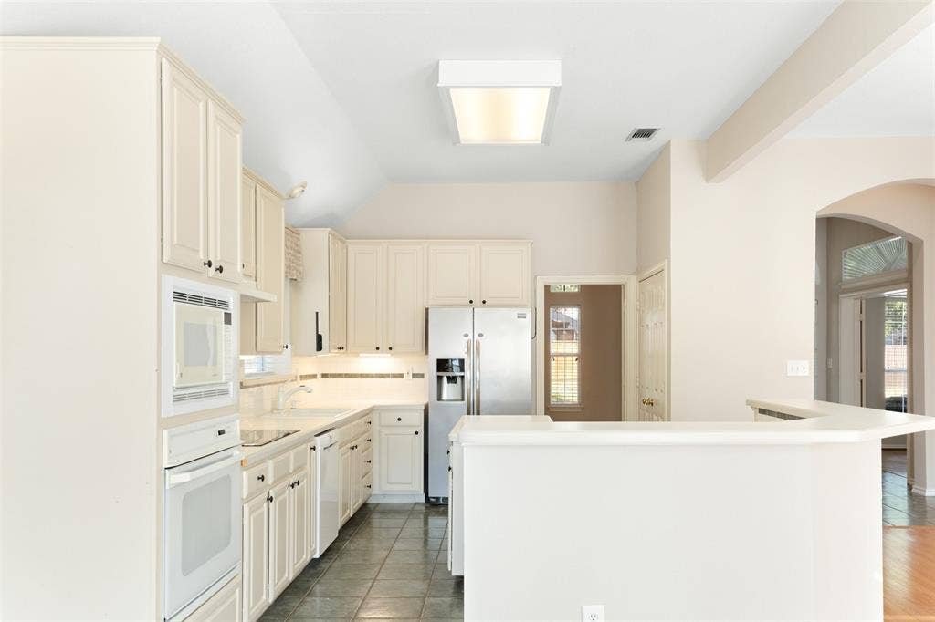 2803 Pheasant Run Drive, McKinney, TX 75072 Kitchen featuring light-toned cabinetry, stainless steel appliances, tile flooring, and a peninsula counter
