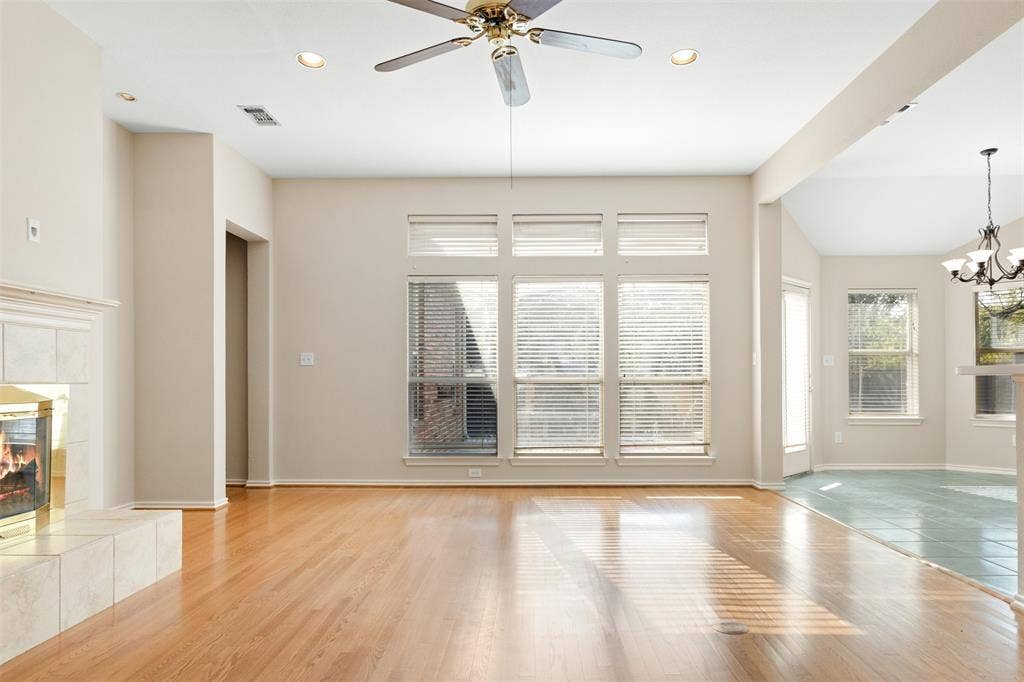 2803 Pheasant Run Drive, McKinney, TX 75072 Living area featuring light-toned wood-finish flooring, a tiled fireplace surround, expansive windows with transom glass, recessed lighting, and a ceiling fan