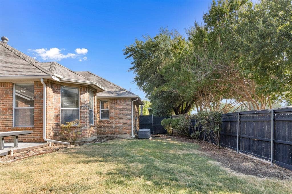 2803 Pheasant Run Drive, McKinney, TX 75072 Brick exterior featuring a hip roof, a concrete patio, and a fenced backyard with mature trees