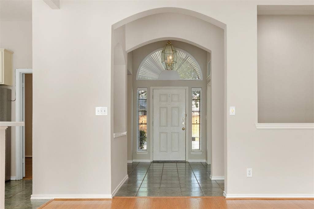 2803 Pheasant Run Drive, McKinney, TX 75072 Entryway featuring a decorative arched architectural opening, tile flooring, and a glass-paneled front door with a semi-circular transom window