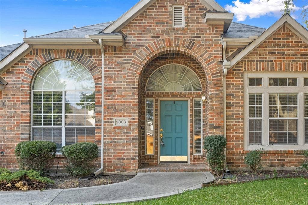 2803 Pheasant Run Drive, McKinney, TX 75072 Exterior facade featuring multi-tonal brick construction, an arched entryway, decorative fanlight windows, and a panelled front door