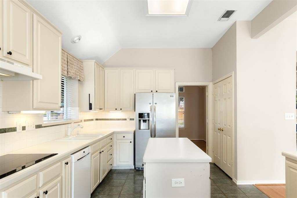 2803 Pheasant Run Drive, McKinney, TX 75072 Kitchen featuring off-white cabinetry, solid surface countertops, tiled backsplash with decorative inlay, stainless steel refrigerator, and tiled flooring