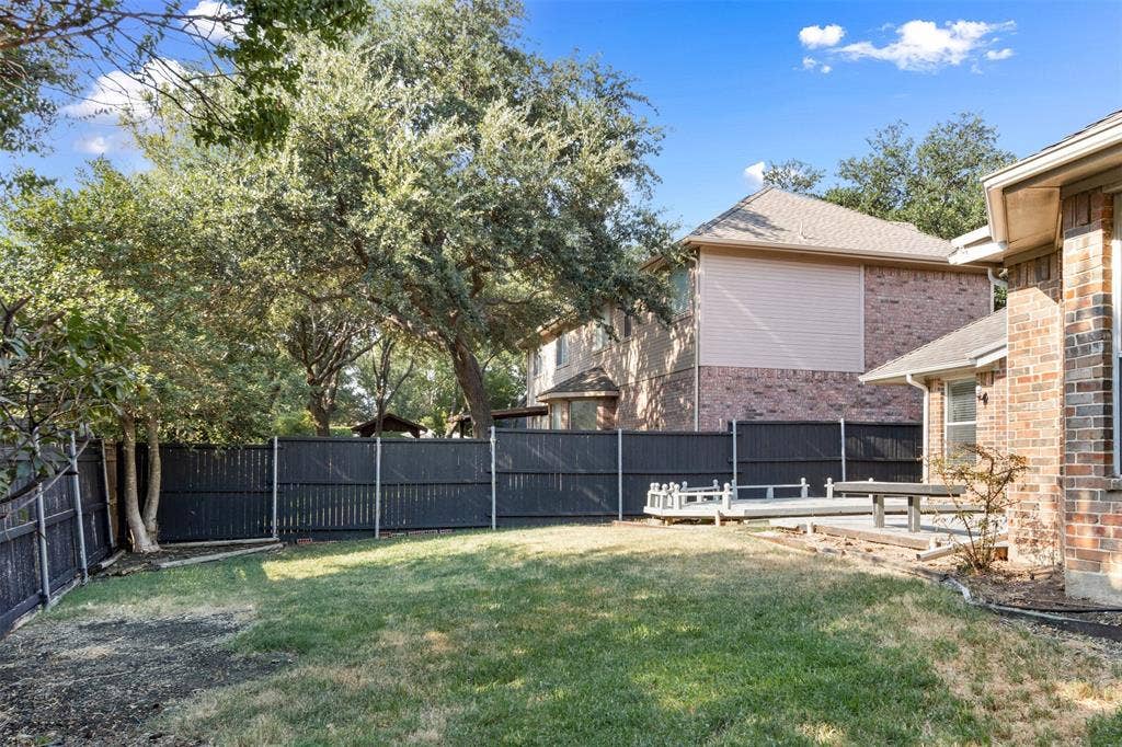 2803 Pheasant Run Drive, McKinney, TX 75072 Backyard featuring a grass lawn, mature trees, a tiered wood deck, and a full-perimeter privacy fence