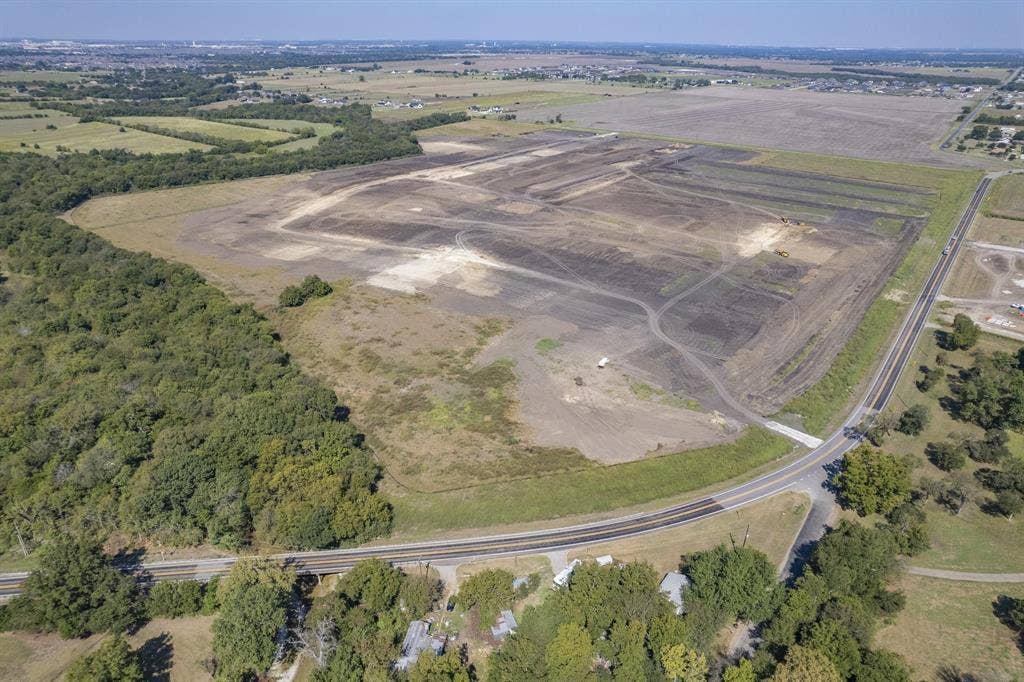 Expansive acreage featuring cleared land, dense perimeter tree lines, and paved road frontage