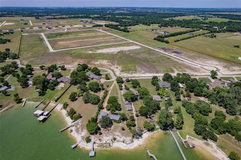 Aerial perspective of waterfront acreage featuring a natural shoreline, multiple private boat docks, and established mature tree canopy