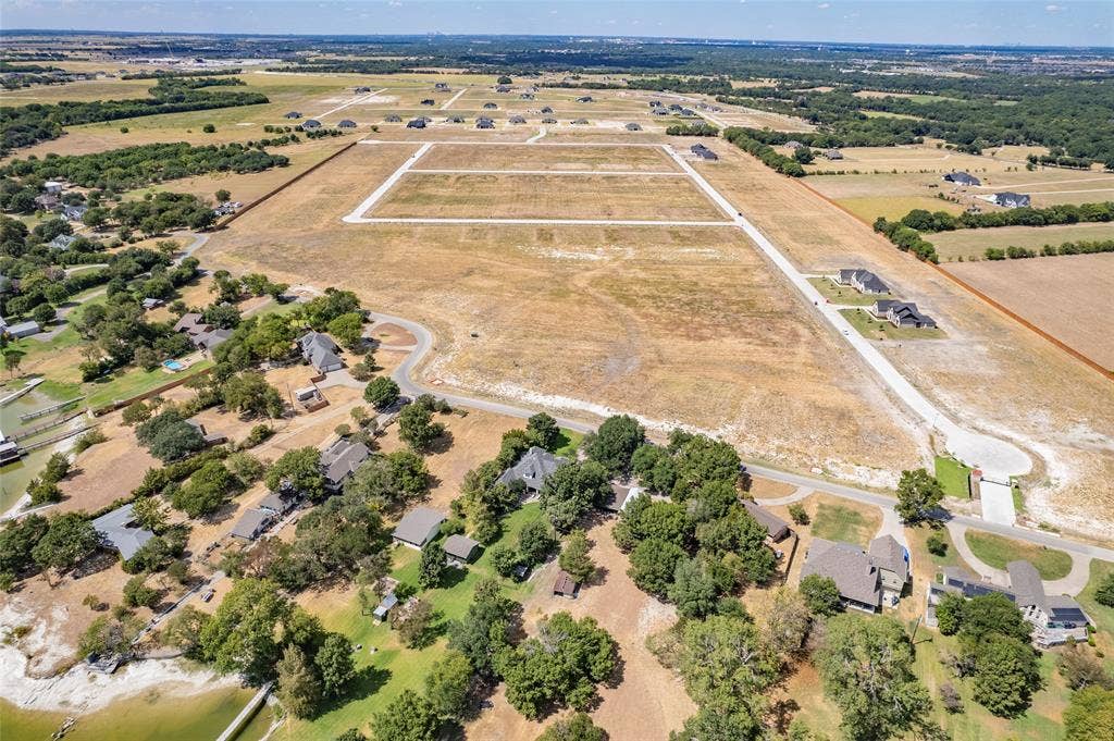 Aerial perspective of a large, undeveloped parcel featuring cleared acreage, paved infrastructure, and mature tree clusters