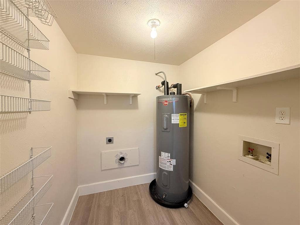 Utility room featuring wood-finish flooring, wall-mounted metal wire shelving, fixed upper shelving, and a water heater