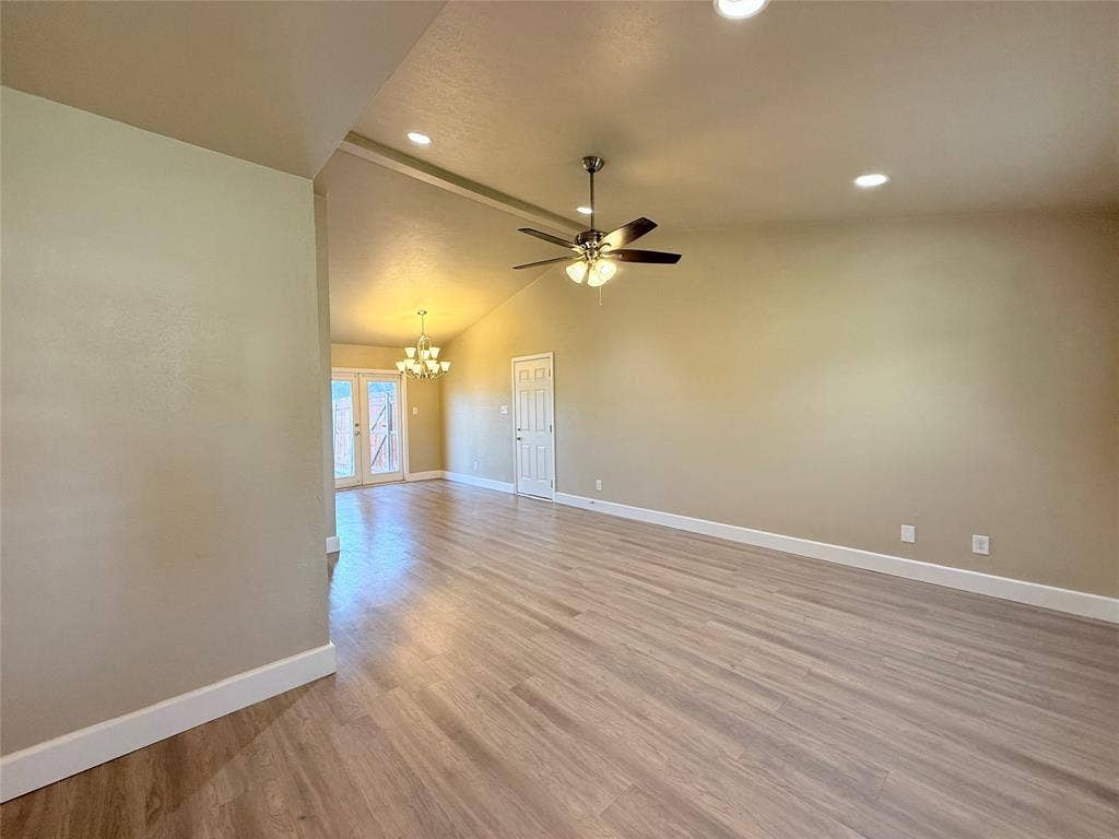 Interior space featuring vaulted ceilings, wood-finish flooring, recessed lighting, a ceiling fan with integrated lighting, and a multi-pane glass door