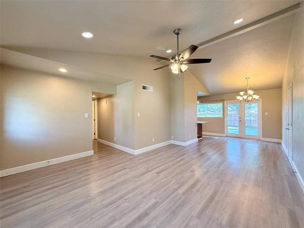 Vaulted ceilings, wood-finish flooring, recessed lighting, ceiling fan with light kit, and double glass-paned doors