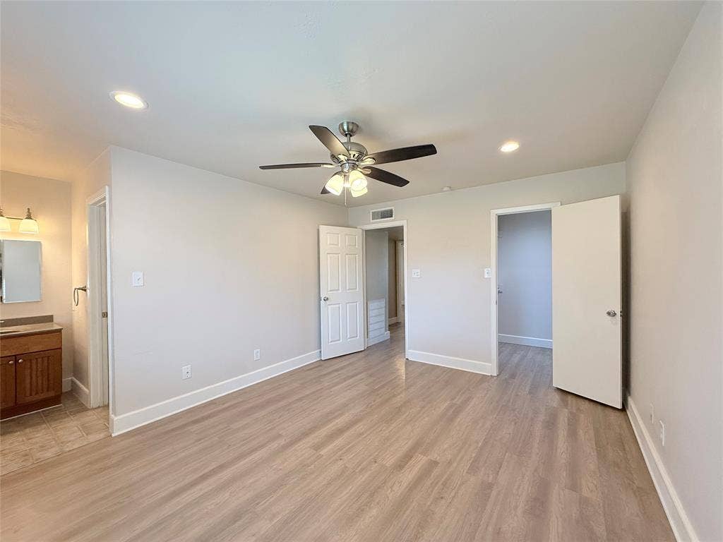 Room featuring wood-finish flooring, recessed lighting, a ceiling fan with integrated light fixture, and solid-core panel doors