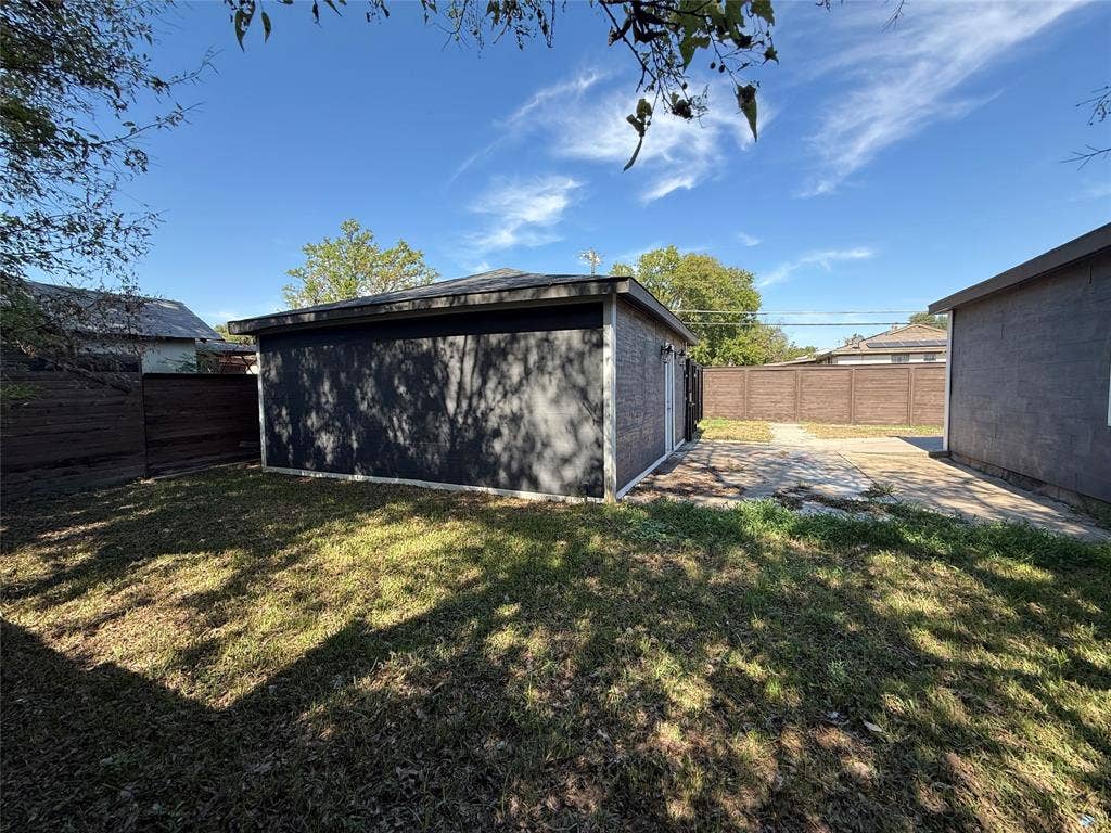 2703 Downing Avenue, Dallas, TX 75216 Detached structure with dark exterior cladding, paved patio area, and enclosed wooden perimeter fencing