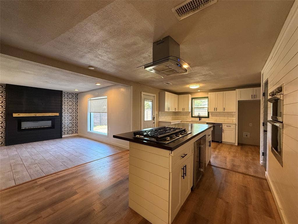 2703 Downing Avenue, Dallas, TX 75216 Kitchen featuring white cabinetry, center island with gas cooktop, built-in double wall oven, and wood-finish flooring