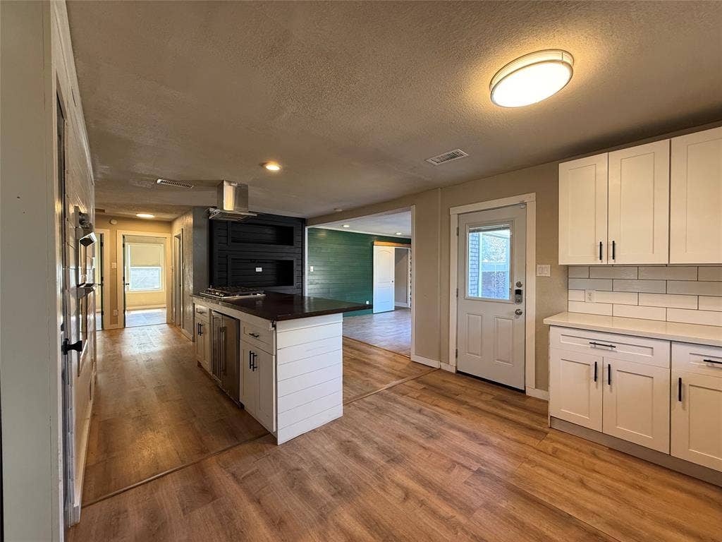 2703 Downing Avenue, Dallas, TX 75216 Kitchen featuring white shaker cabinetry, wood-finish flooring, a central island with a built-in cooktop, stainless steel ventilation hood, and white subway tile backsplash