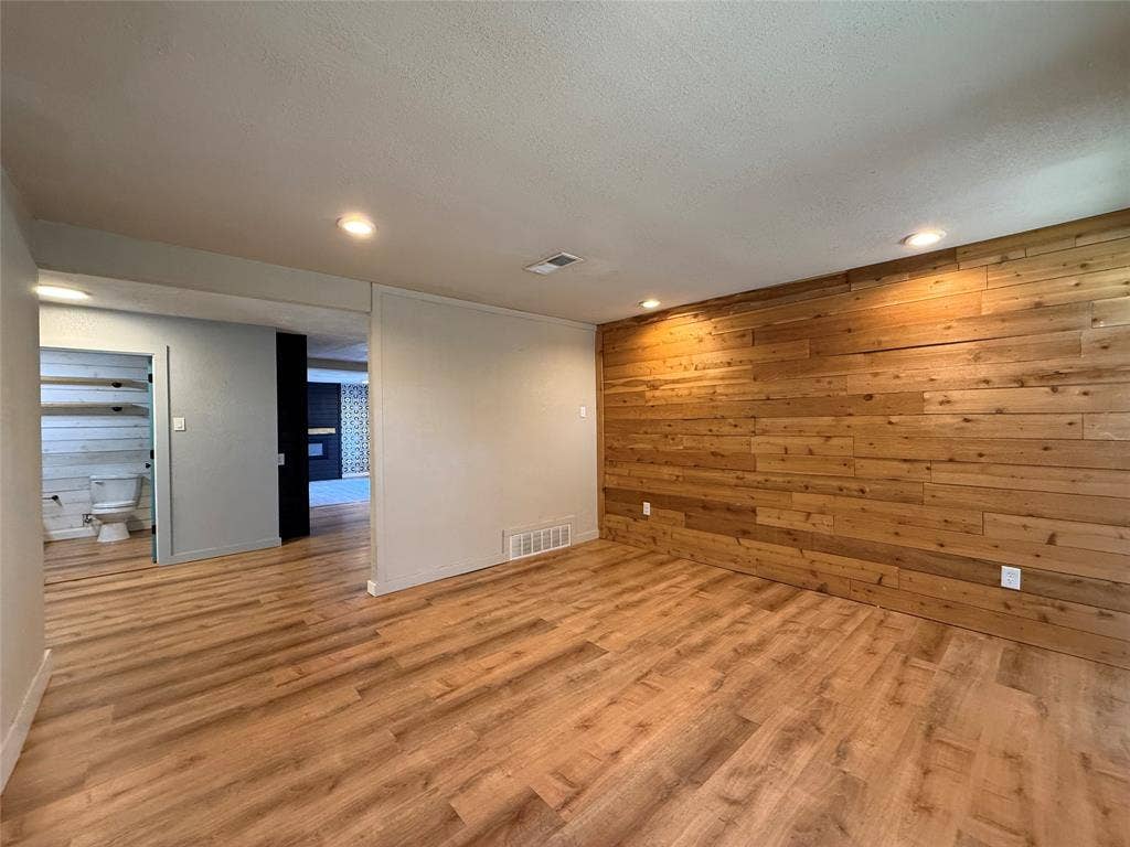 2703 Downing Avenue, Dallas, TX 75216 Interior space featuring wood-finish flooring, a horizontal wood-plank accent wall, recessed lighting, and wall-mounted shelving