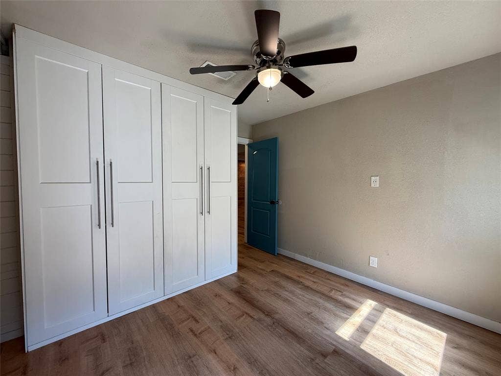 2703 Downing Avenue, Dallas, TX 75216 Built-in floor-to-ceiling cabinetry with shaker-style doors, wood-finish flooring, ceiling fan with integrated light fixture, and paneled door