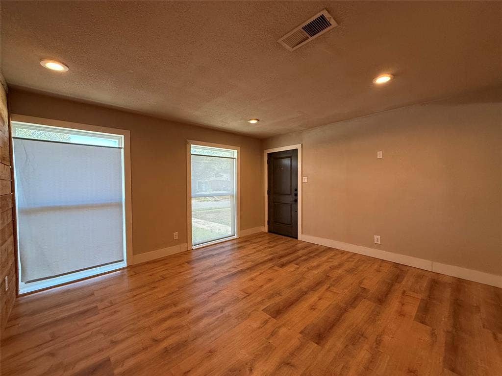 2703 Downing Avenue, Dallas, TX 75216 Interior space featuring wood-finish flooring, two large windows, recessed lighting, and a dark-toned solid door