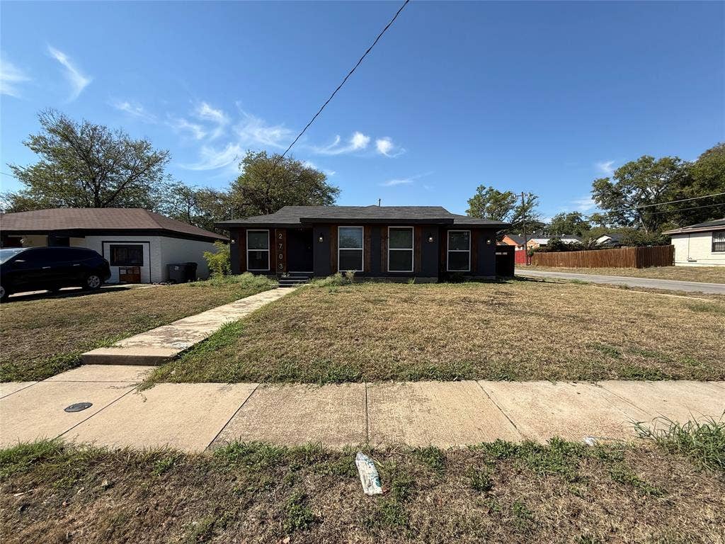 2703 Downing Avenue, Dallas, TX 75216 Single-story residence featuring a dark-toned exterior facade, prominent wood-trim window detailing, a hip roof, and a concrete walkway