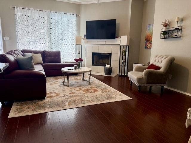 11159 Covey Lane, Frisco, TX 75035 Living area featuring dark wood-finish flooring, a fireplace with a light-toned tile surround, and a classic white mantel