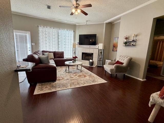 11159 Covey Lane, Frisco, TX 75035 Living area featuring wood-finish flooring, a tiled fireplace with a mantle, and a ceiling fan with integrated lighting