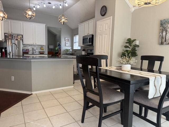 11159 Covey Lane, Frisco, TX 75035 Kitchen featuring white cabinetry, solid-surface countertops, tile flooring, spherical pendant lighting, and vaulted ceilings