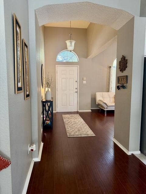11159 Covey Lane, Frisco, TX 75035 Entryway featuring high ceilings, arched architectural detailing, wood-finish flooring, a pendant light fixture, and a white front door with a half-moon transom window