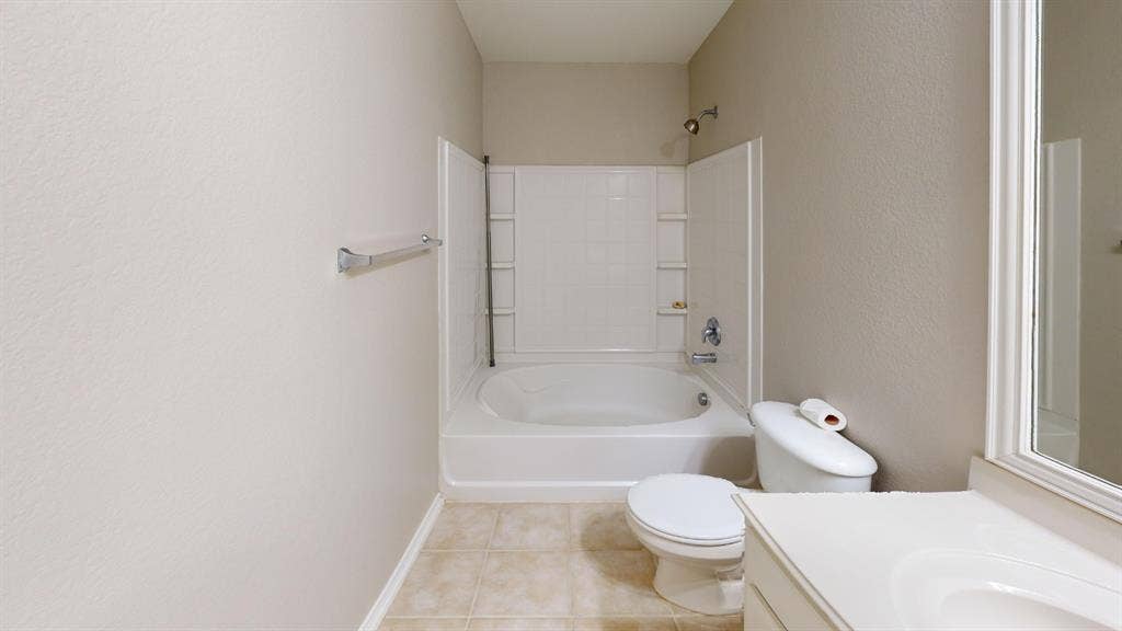 Bathroom featuring a soaking tub, integrated shower surround with built-in shelving, tile flooring, and a single-basin vanity