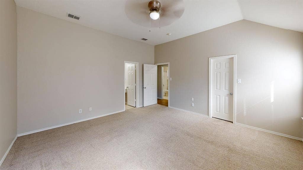 Vaulted ceilings, neutral wall tones, carpeted flooring, and a ceiling fan with integrated lighting