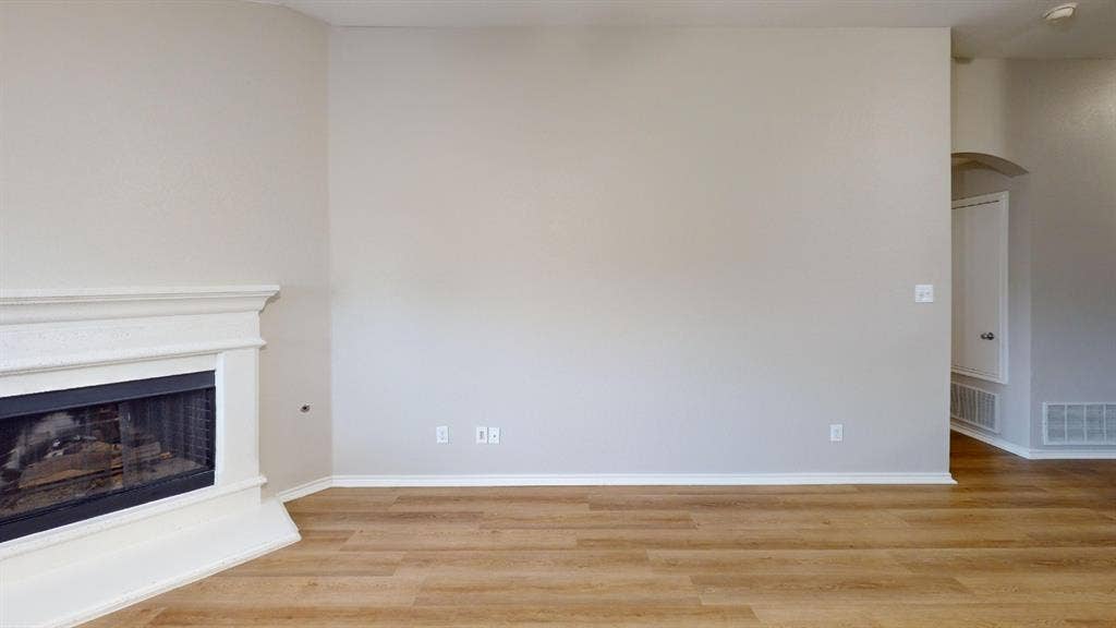 Fireplace with a classic white mantel, neutral wall tones, and wood-finish flooring