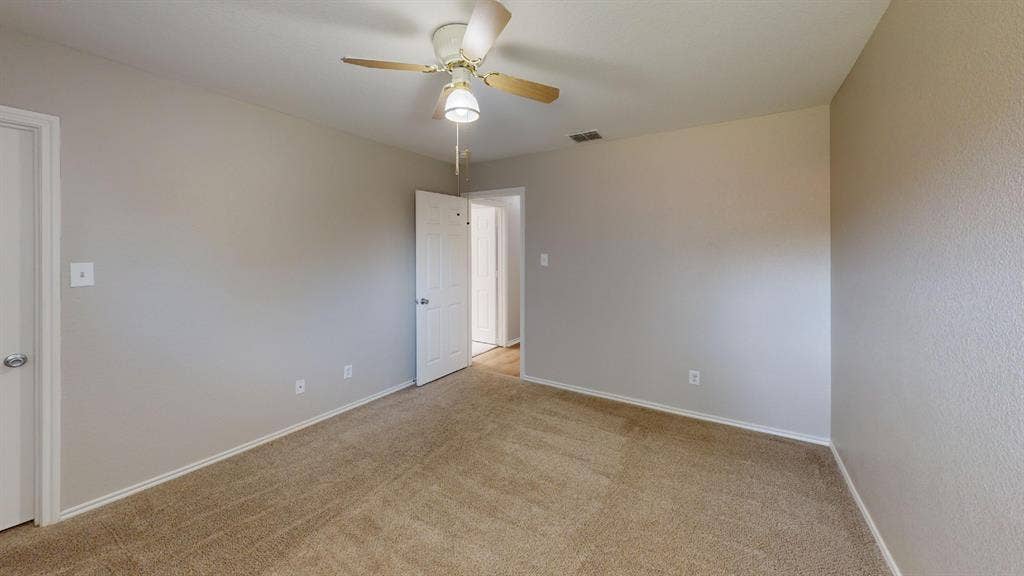 Neutral-toned walls, wall-to-wall carpeting, ceiling fan with integrated lighting, and multi-panel interior doors