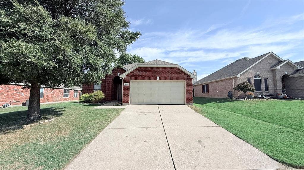 Exterior featuring red brick masonry, a concrete driveway, a multi-car garage, and mature shade trees