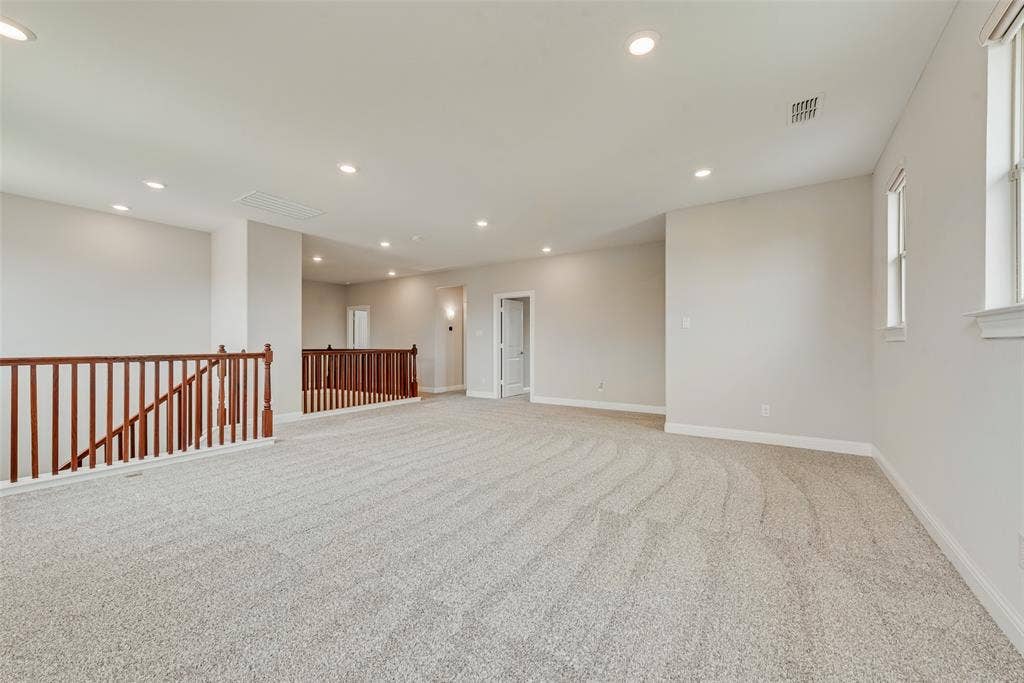 9829 Sharps Drive, Frisco, TX 75035 Open floor plan featuring recessed lighting, neutral carpeting, and a wood-slat railing