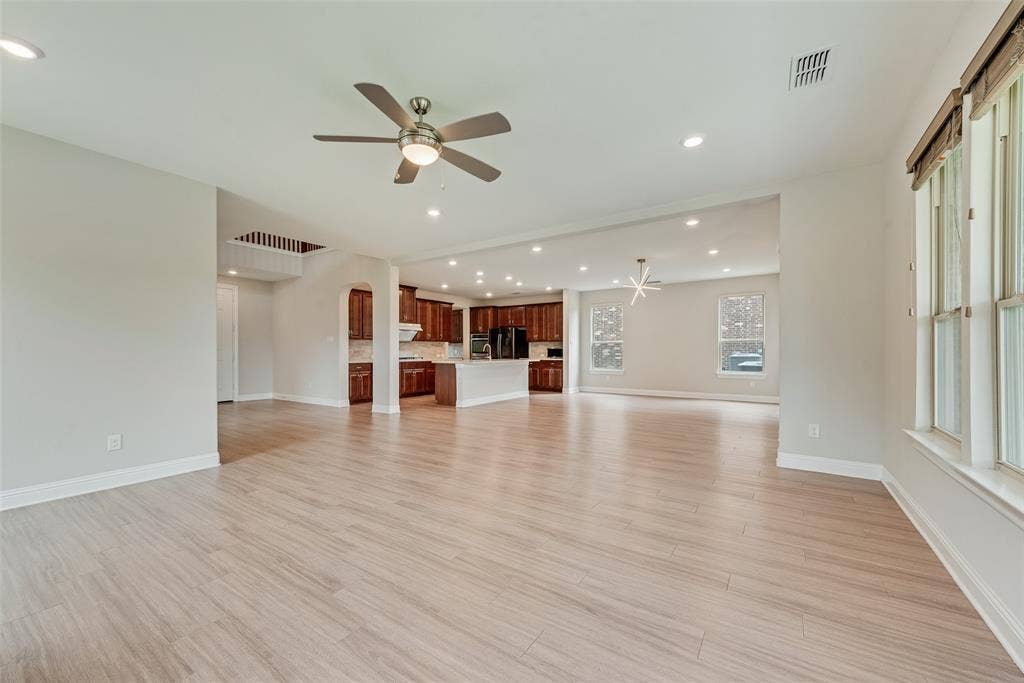 9829 Sharps Drive, Frisco, TX 75035 Open-concept interior featuring wood-finish flooring, recessed lighting, a ceiling fan, and a kitchen with dark-finish cabinetry and a central island