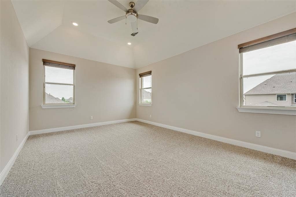 9829 Sharps Drive, Frisco, TX 75035 Vaulted ceiling featuring a central brushed-nickel ceiling fan, recessed lighting, neutral carpeting, and multiple windows with installed roller shades