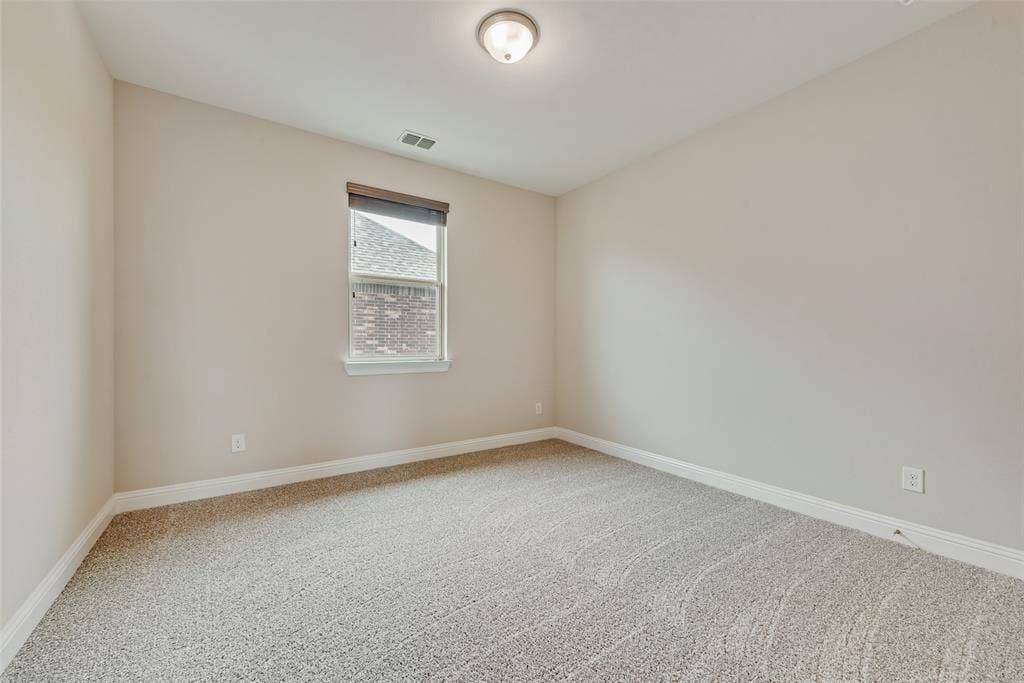 9829 Sharps Drive, Frisco, TX 75035 Neutral-toned interior space featuring wall-to-wall carpeting, a single-pane window with a roller shade, and a flush-mount ceiling light fixture