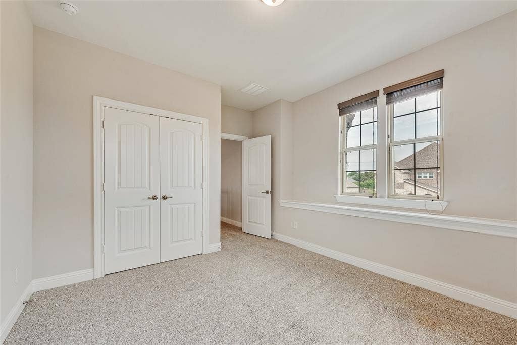 9829 Sharps Drive, Frisco, TX 75035 Neutral-toned interior featuring wall-to-wall carpeting, double-panel closet doors, grid-patterned windows, and chair rail molding