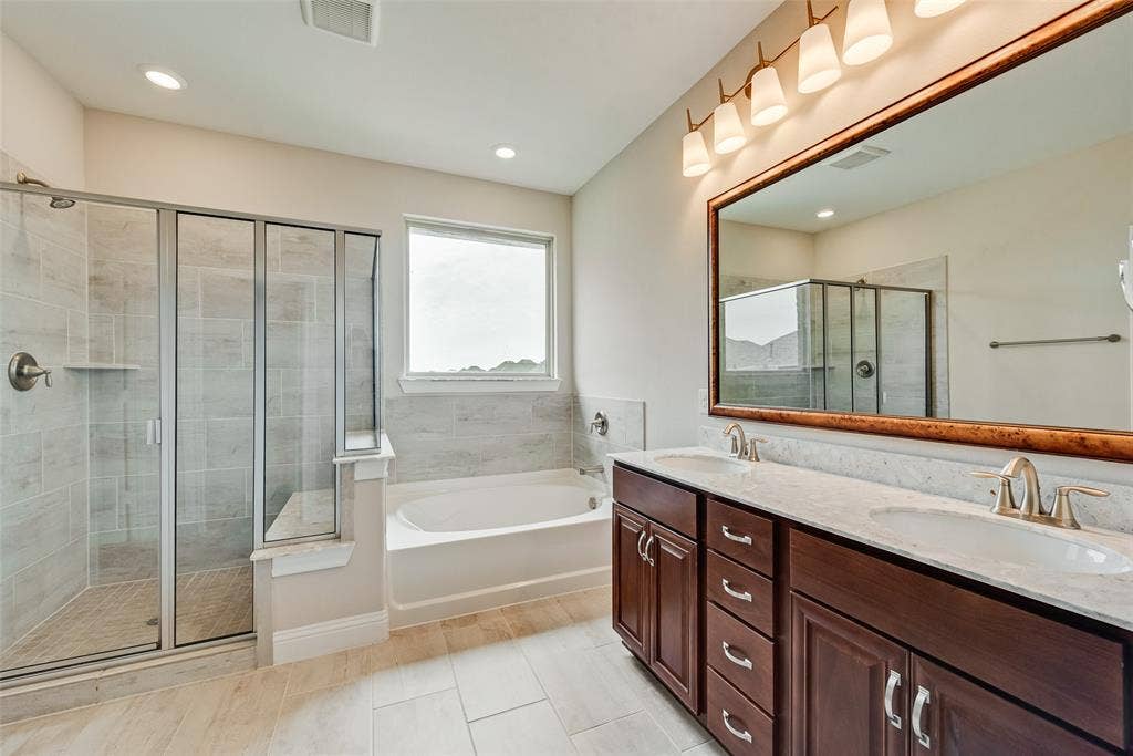9829 Sharps Drive, Frisco, TX 75035 Double vanity with dark wood cabinetry, solid surface countertops, dual undermount sinks, and a large framed mirror