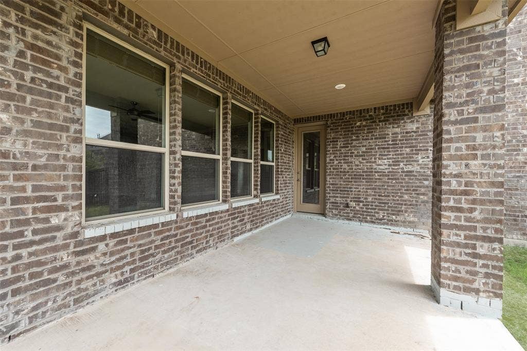 9829 Sharps Drive, Frisco, TX 75035 Covered outdoor patio featuring brick masonry walls, concrete flooring, recessed lighting, and multiple tall windows