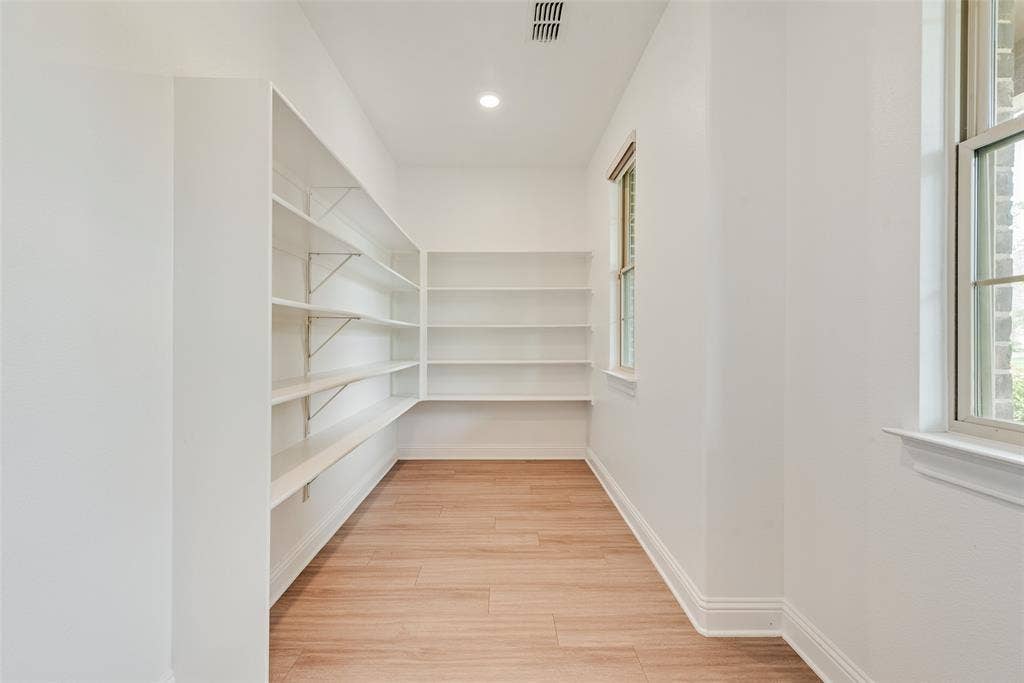9829 Sharps Drive, Frisco, TX 75035 Storage space featuring wood-finish flooring, white walls, and multiple tiers of wall-mounted shelving