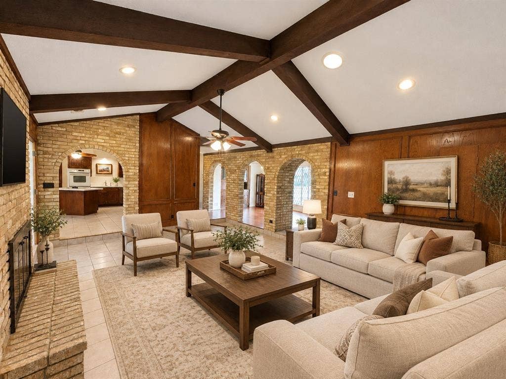 Vaulted ceiling with exposed wood beams, brick masonry fireplace, wood wall paneling, and arched brick entryways