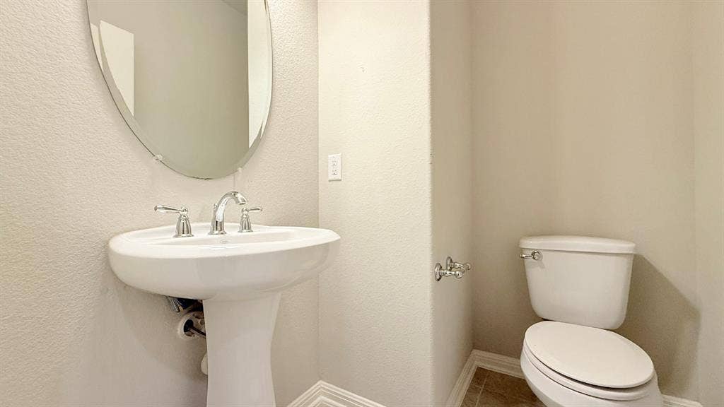 2937 Mossy Springs Drive, Leander, TX 78641 Pedestal sink with polished chrome widespread faucet, oval wall-mounted mirror, and tile flooring