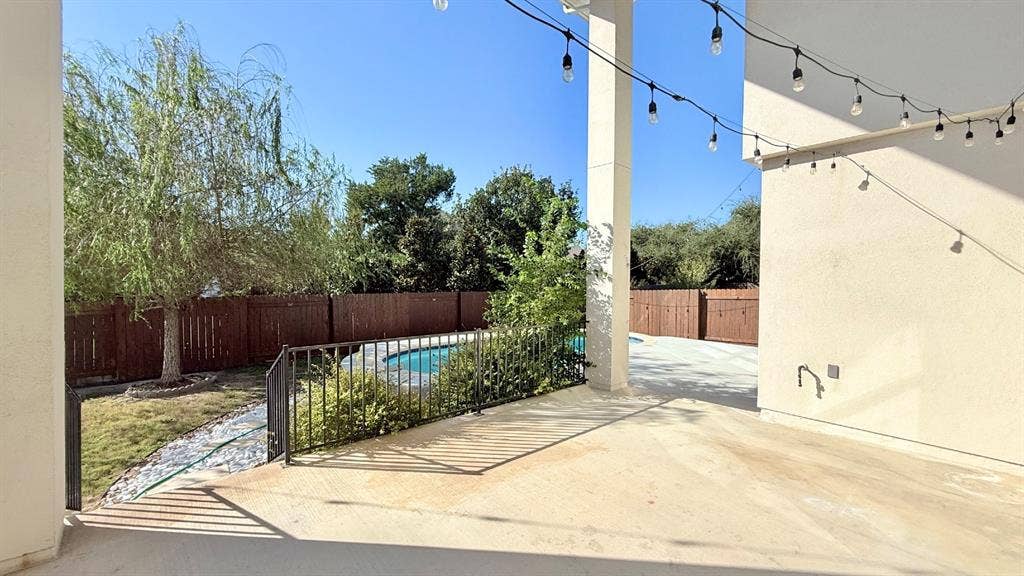 2937 Mossy Springs Drive, Leander, TX 78641 Covered patio featuring concrete flooring, swimming pool with metal safety fencing, and wood-panel perimeter privacy fencing
