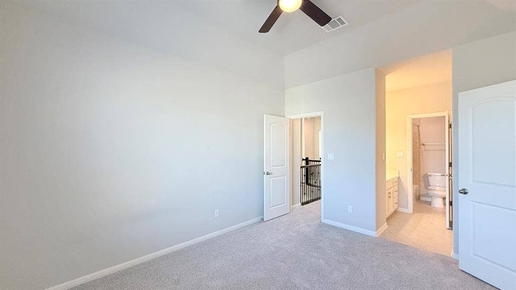 2937 Mossy Springs Drive, Leander, TX 78641 Spacious room with high ceilings, neutral wall color, plush carpeted flooring, and a mounted ceiling fan, featuring an attached bathroom with white cabinetry