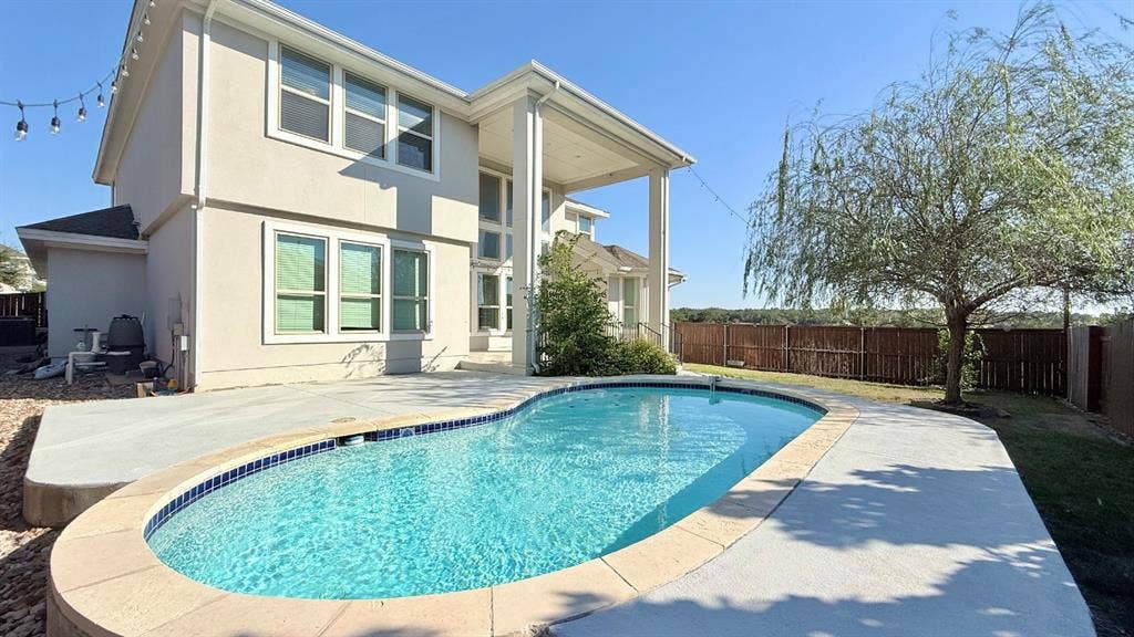 2937 Mossy Springs Drive, Leander, TX 78641 Two-story exterior featuring a stucco finish, a covered rear patio, a swimming pool with stone-style coping, and perimeter wood fencing