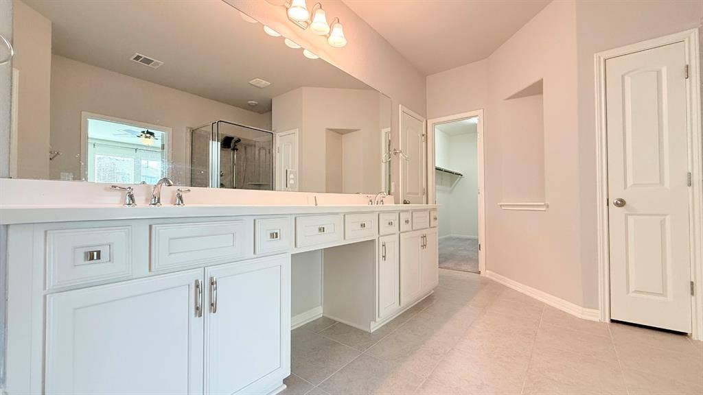 2937 Mossy Springs Drive, Leander, TX 78641 Double vanity featuring white cabinetry, solid-surface countertops, dual undermount sinks, and a full-width mirror